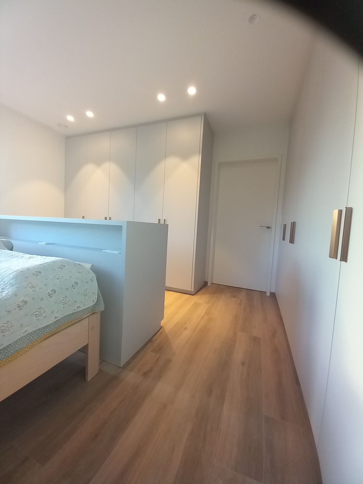 Slaapkamer met grijze dressing met messing flapgrepen langs de wand en een kastenwand achteraan in Koksijde