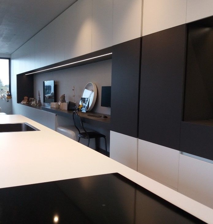 Wit werkblad met zwarte kookplaat voor een strakke wand van zwart en wit laminaat met ledstrip