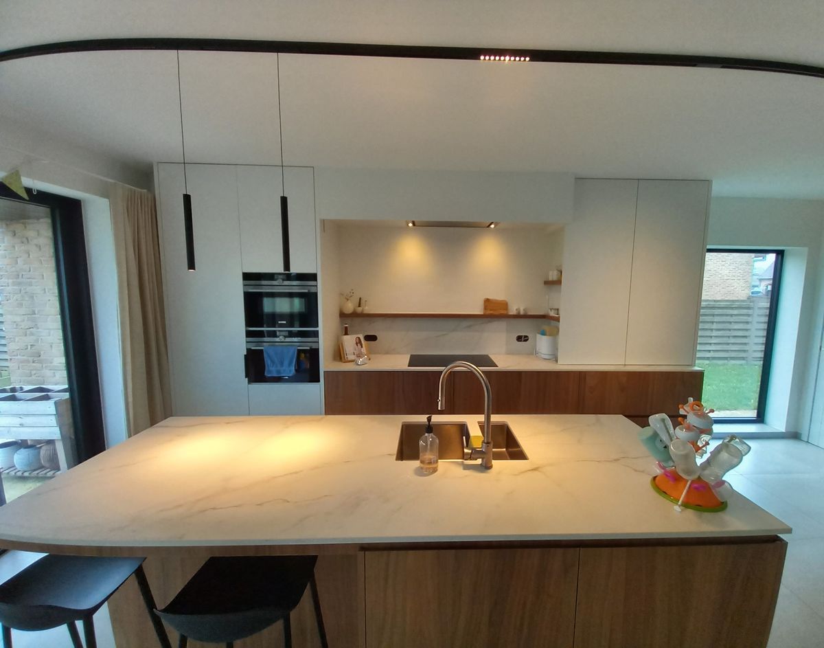 Open keuken in Vleteren met eiland in shinnoki, wit Uniceramica-werkblad en hoge witte greeploze kasten