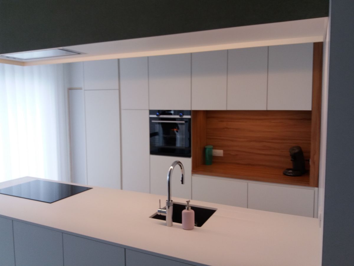 Witte keuken in Ingelmunster in laminaat met ingebouwde oven, houtkleurige nis en eiland met spoelbak en kookplaat