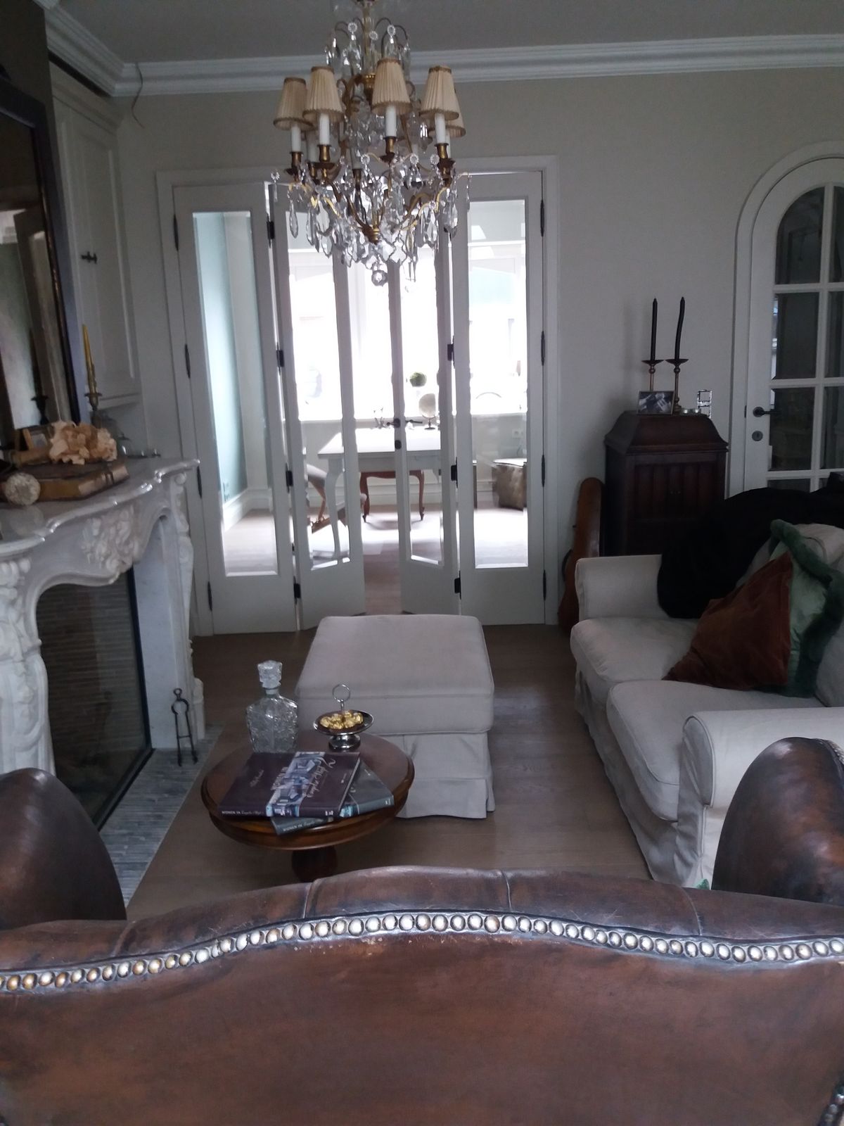 Klassiek ingerichte woonkamer met lederen zetels, kroonluchter en haardwand met marmeren schouw links