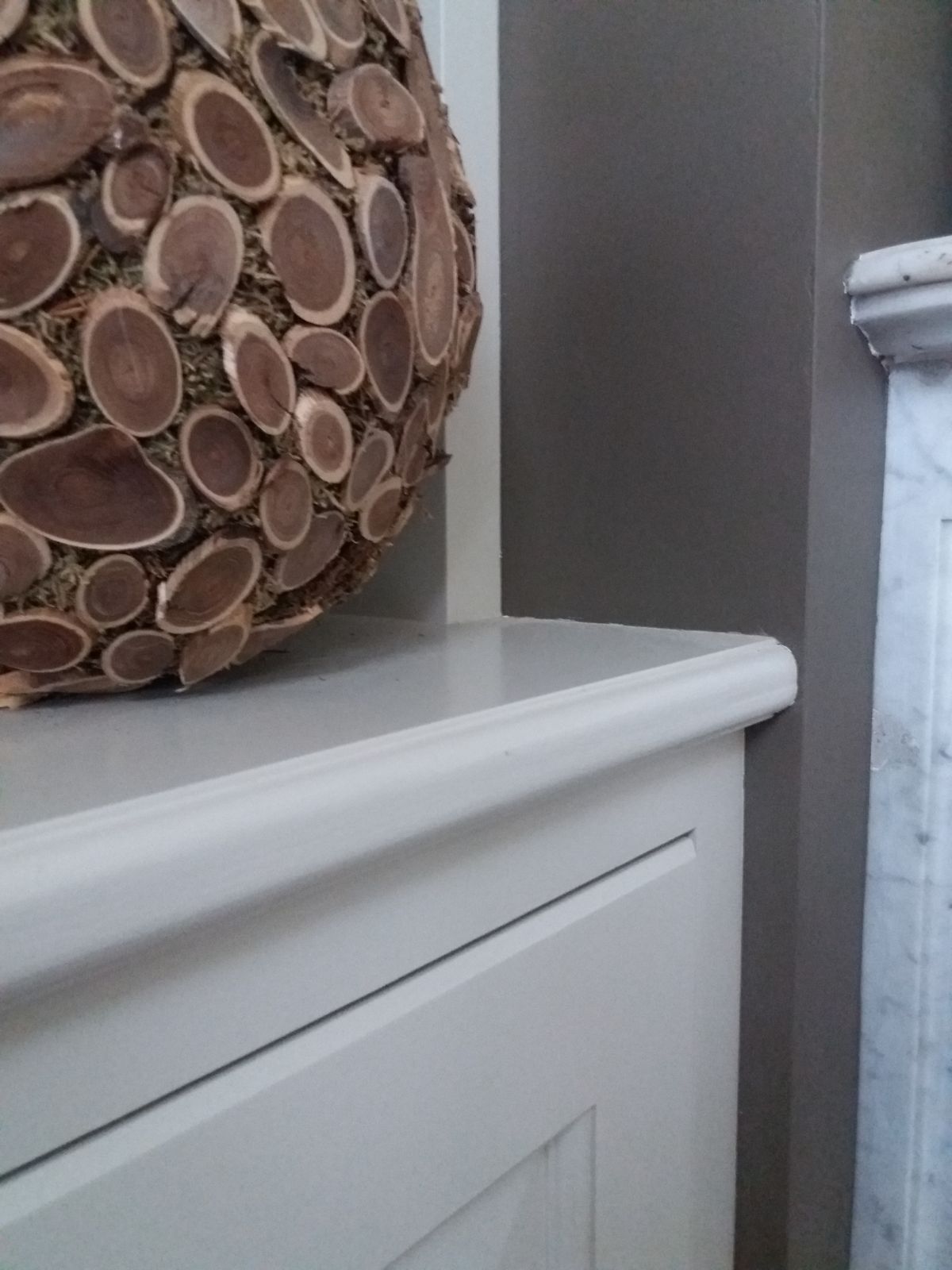 Detail van het geprofileerde tablet en de paneeldeur in geschilderde mdf naast de marmeren schouw
