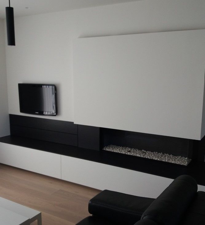 Leefruimte in Langemark-Poelkapelle met witte onderkasten, zwart Dekton-blad, tv aan de muur en gashaard