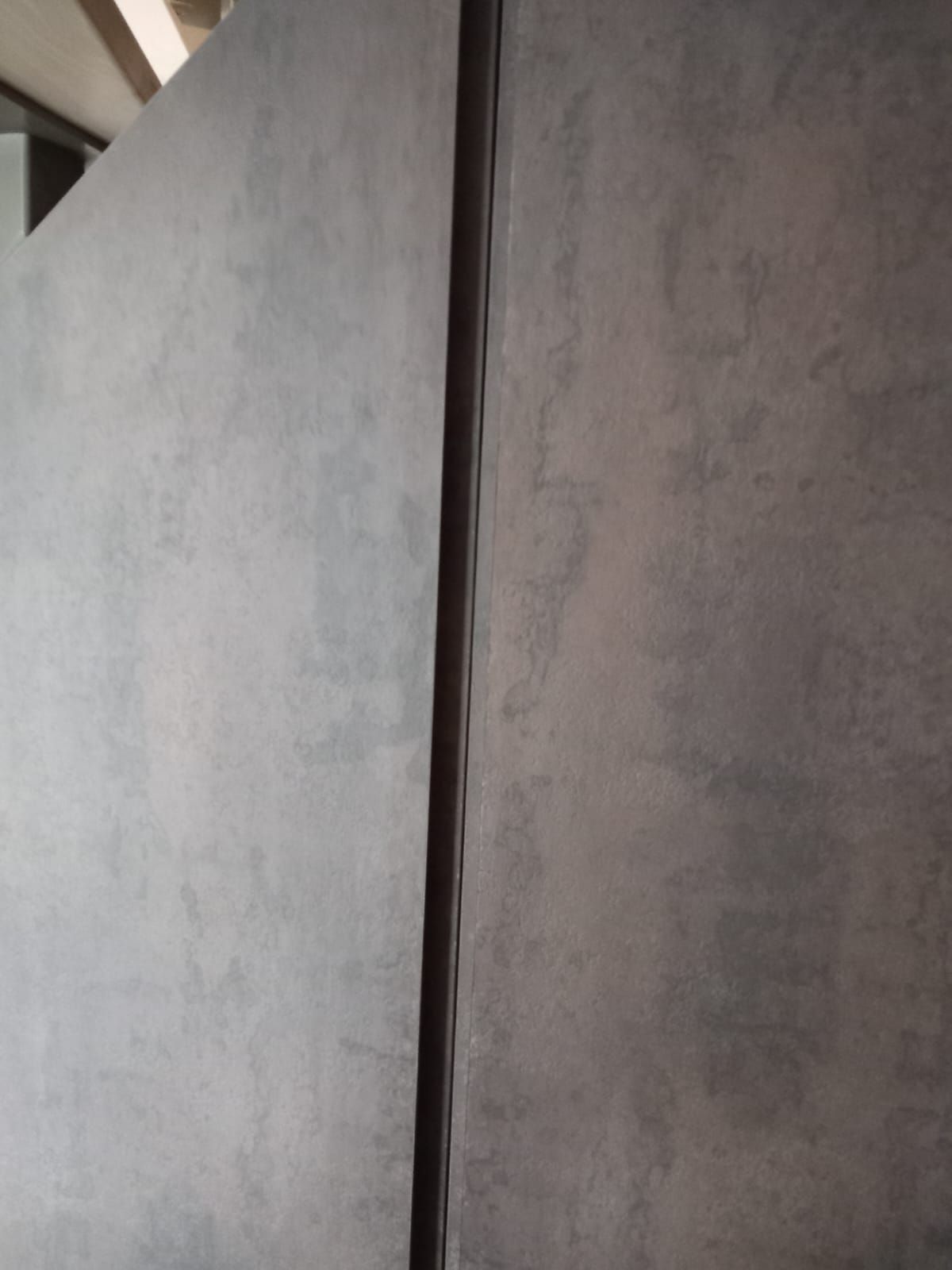 Close-up van de verticale greepsleuf tussen twee donkergrijze kastdeuren in laminaat
