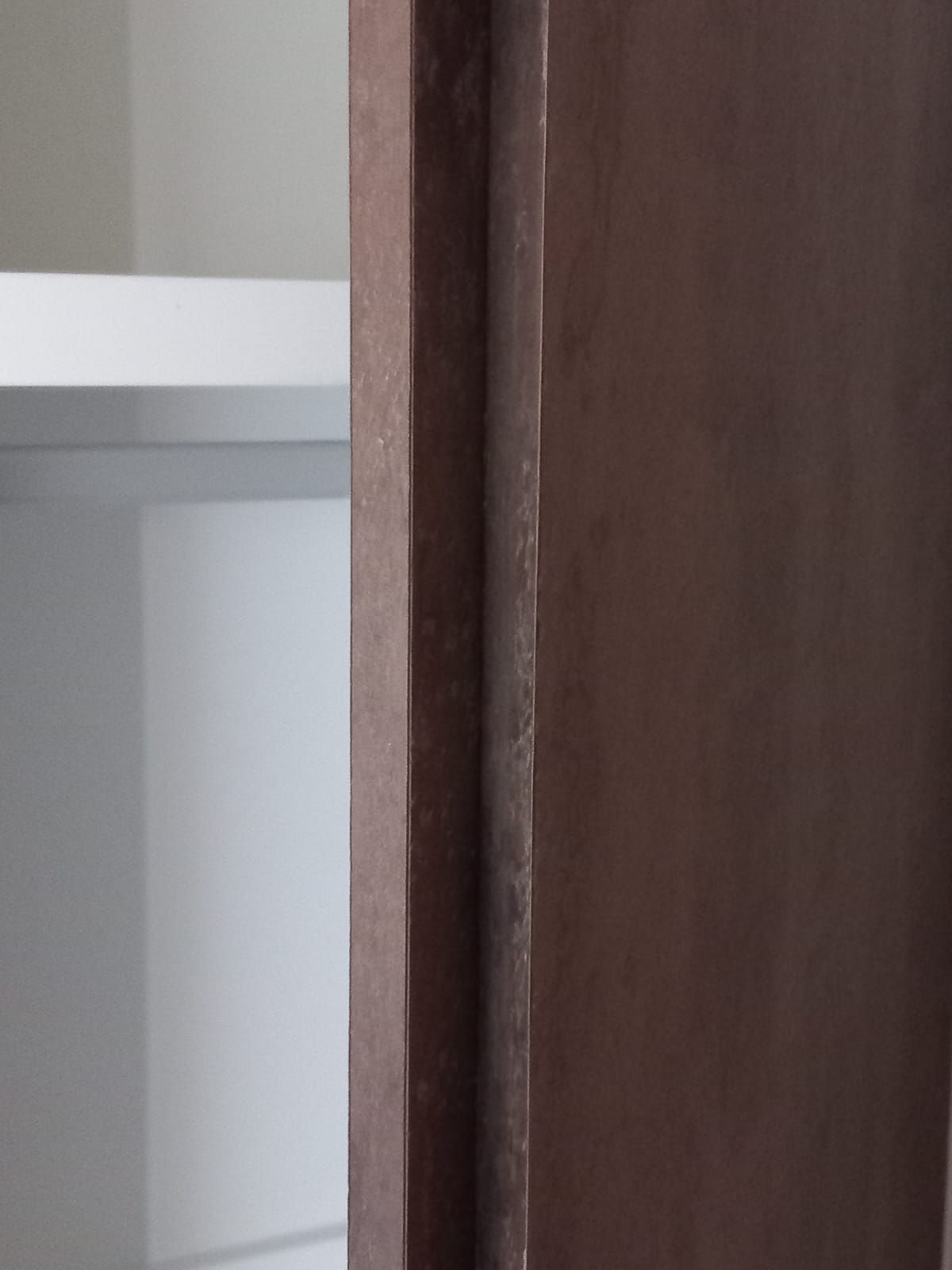 Close-up van de zijkant en greeplijst van een kastdeur in donker laminaat