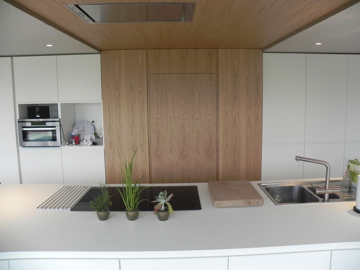Wit eiland met kookplaat en spoelbak voor een fineer kastenwand in lijn met het fineer plafond, in Moorslede