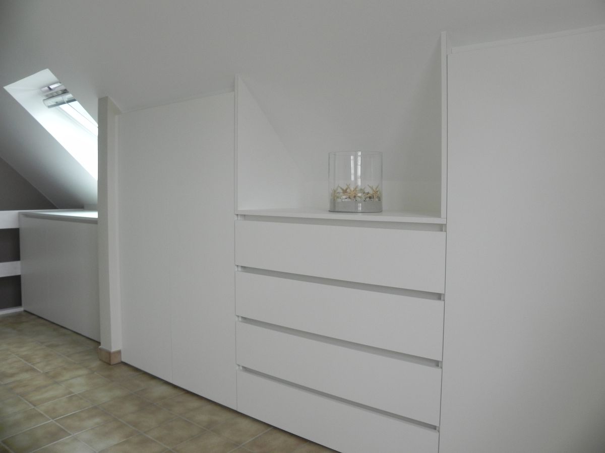 Witte dressing in wit laminaat met nis boven een ladenkast, onder het schuine dak naast een dakraam