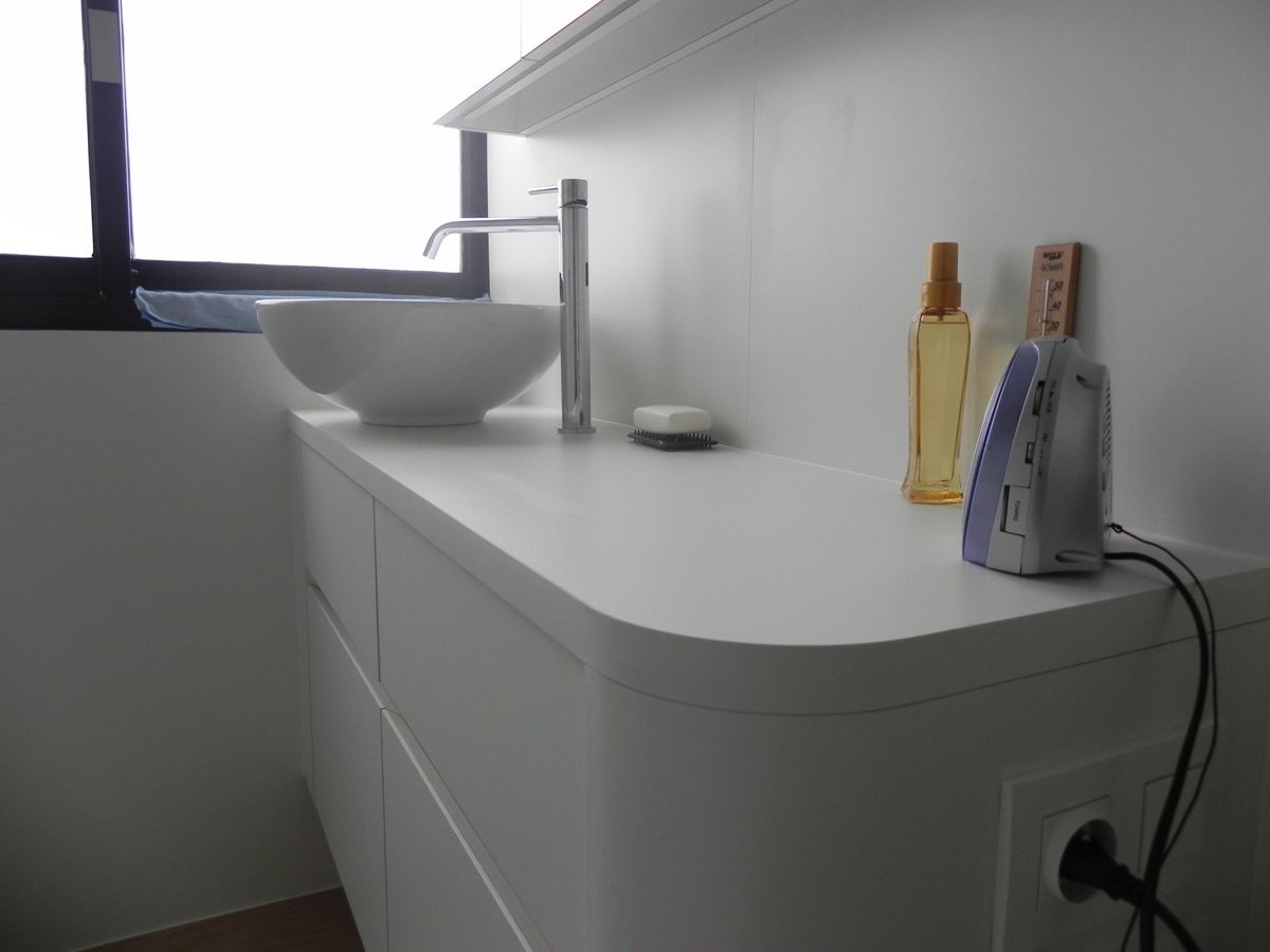 Witte badkamermeubel met afgeronde hoek, opbouwwaskom en hoge kraan in een appartement in Ieper