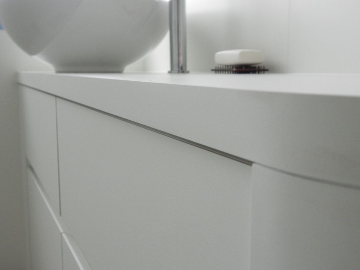 Detail van de afgeronde witte badkamerkast met greeploze lades en opbouwwaskom