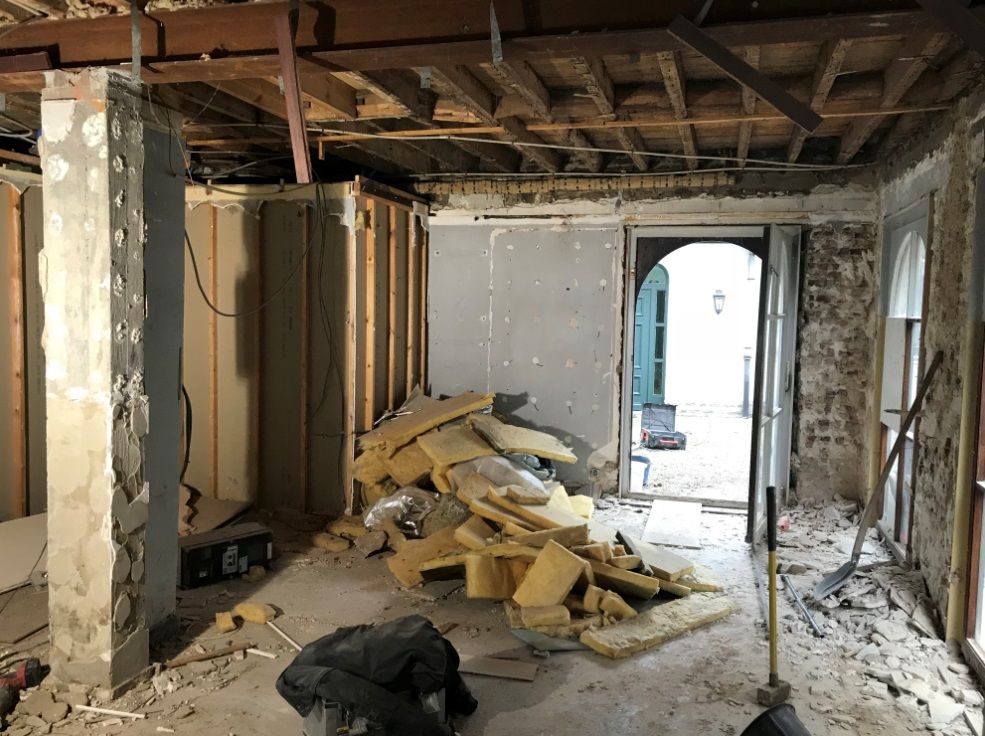 Situatie voor de renovatie: gestripte ruimte met blootgelegde balken, puin en isolatiemateriaal