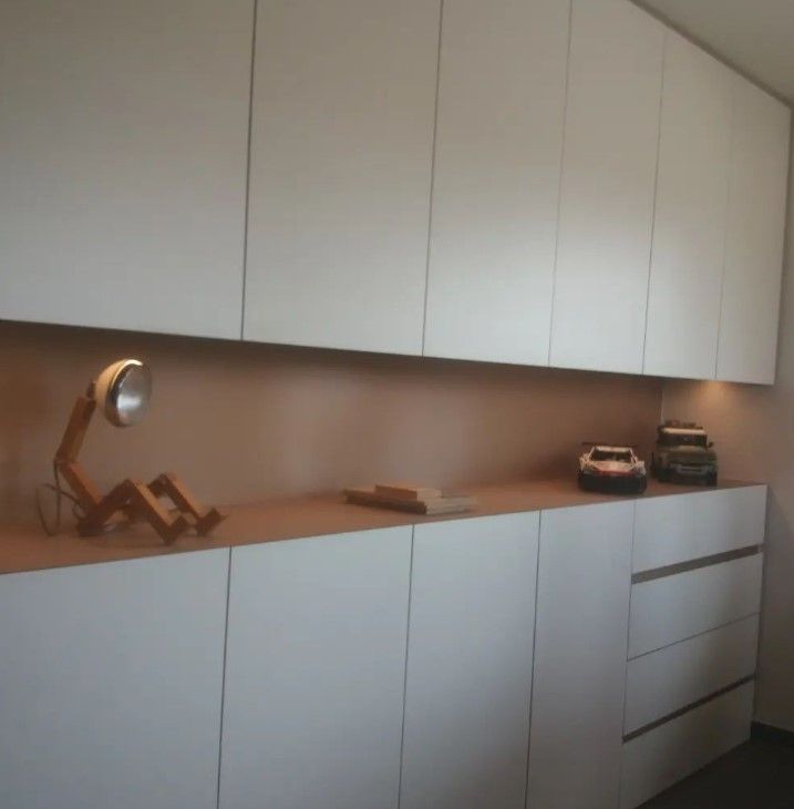 Witte greeploze wandkast in Ieper met boven- en onderkasten, lades en een nis met warme ledstrip