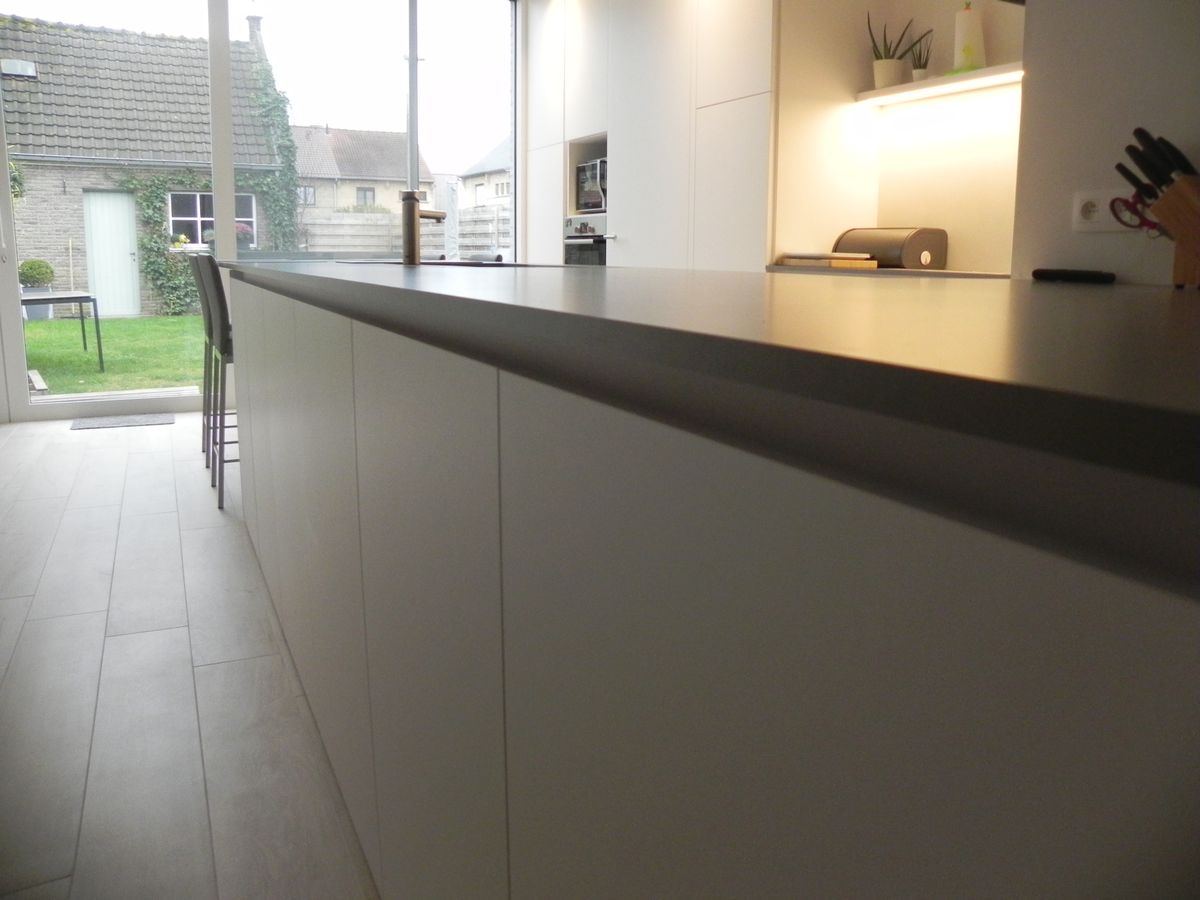 Moderne keuken in Ieper met grepenloos eiland in wit laminaat en donker werkblad, met zicht op de tuin