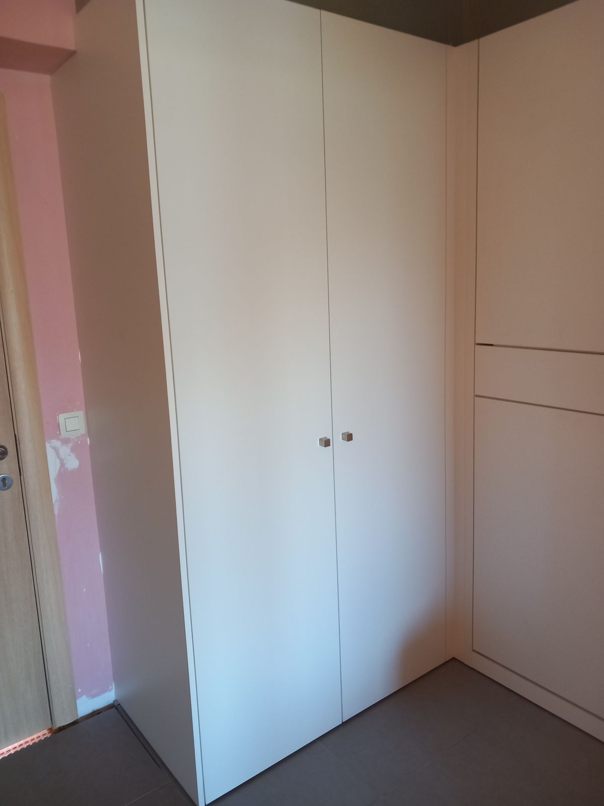 Hoge witte maatkast in mat laminaat met dubbele deur in een appartement in Middelkerke
