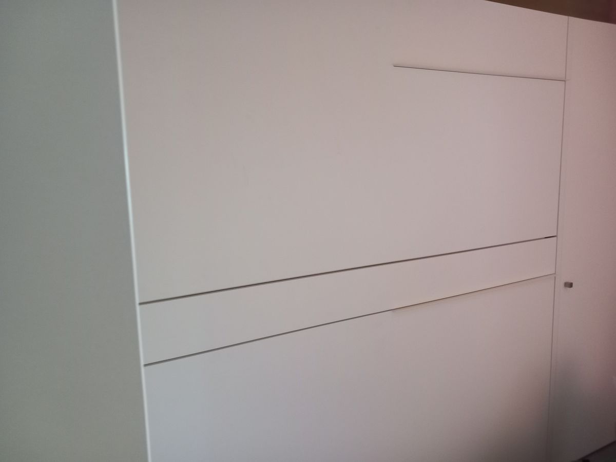 Detail van de witte fronten in mat laminaat van een inklapbaar bed in de kastenwand