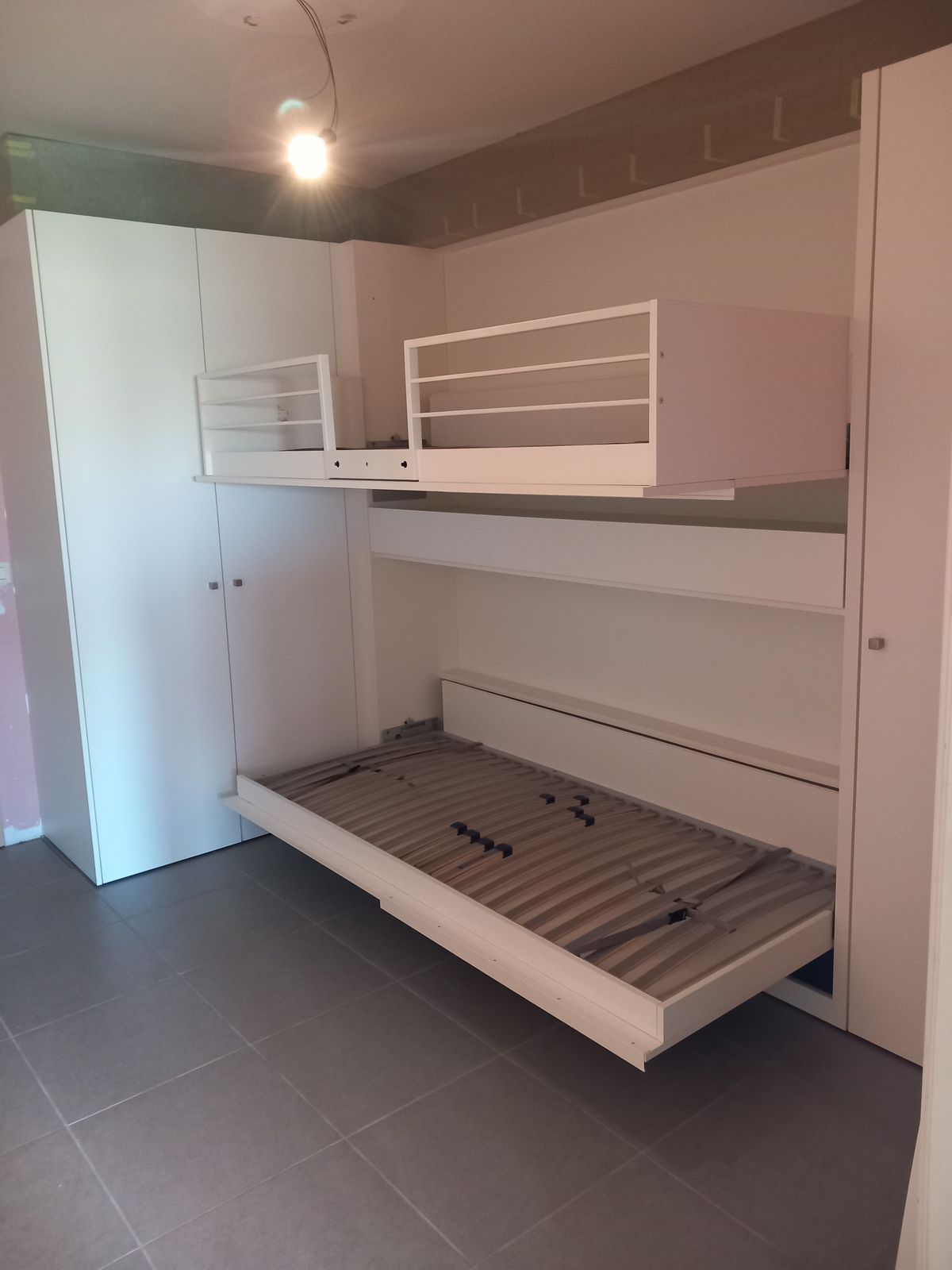 Uitgeklapt stapelbed in witte maatkast: bovenste bed met reling en onderste bed met lattenbodem