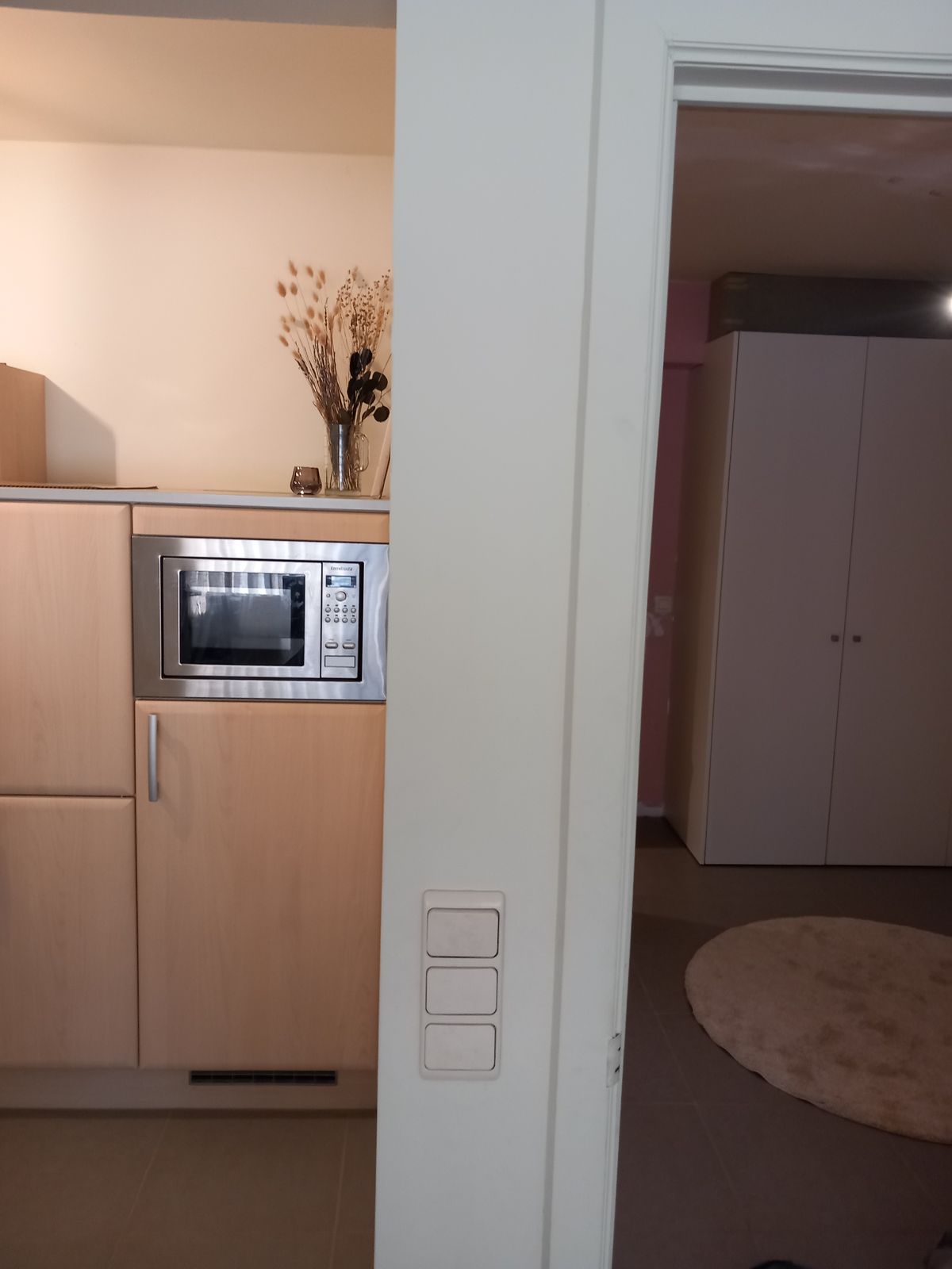 Doorkijk van de kitchenette naar de slaapruimte met witte maatkasten in mat laminaat